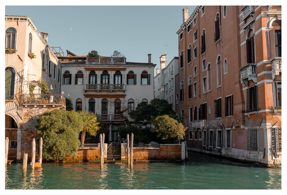 Szene aus Venedig vom Wasser aus aufgenommen: ein kleiner ummauerter Garten am Kanal, dahinter ein Palazzo. Links und rechts weitere Pallazi und ein schmaler Kanal links. Gedeckte Farben, viel Orange/Rot was einen kontrast mit dem Wasser bildet.