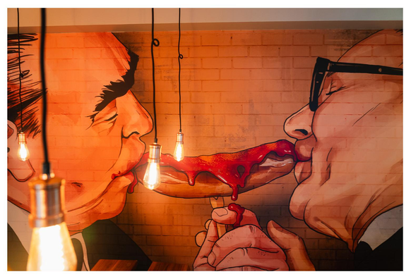 Das bekannte Breschnew/Honecker Bruderkuss-Bild in freier interpretation in einer Berliner Currywurst-Bude. Leonid und Erich küssen sich nicht, sondern nuckeln jeweils an einem Ende der Currywurst.