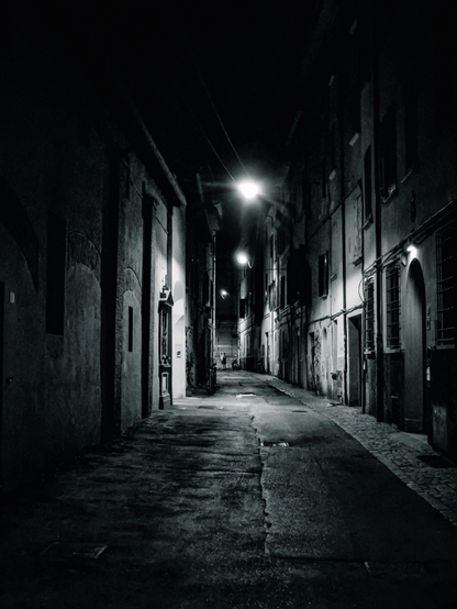 A black and white photo of a practically empty street at night in Bologna