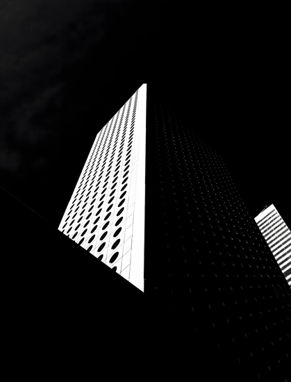 Black and White of a skyscraper with one side completely blocked from the morning sunshine.