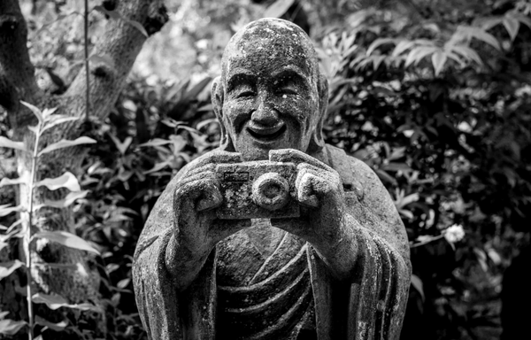 Estàtua de disciple de Buda amb càmera fotogràfica al temple de Jokeigi, Japó.