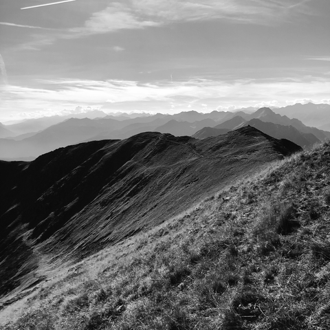 Un prato scosceso su un versante della montagna con molte cime di montagne in lontananza