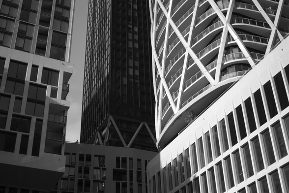 Photo of tall buildings, one is brightly lit, others are in shade.