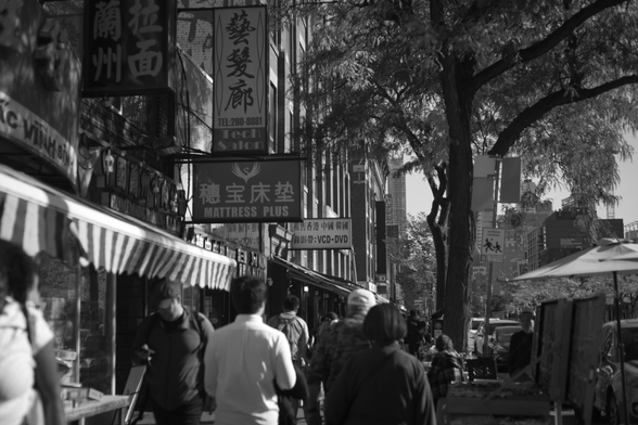 Photo of pedestrians along Spadina Avenue, sings for various Chinese businesses are visible.
