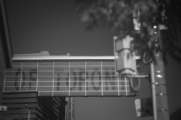 A photo of a glass cantilever structure with "OF TORONTO" written across it.